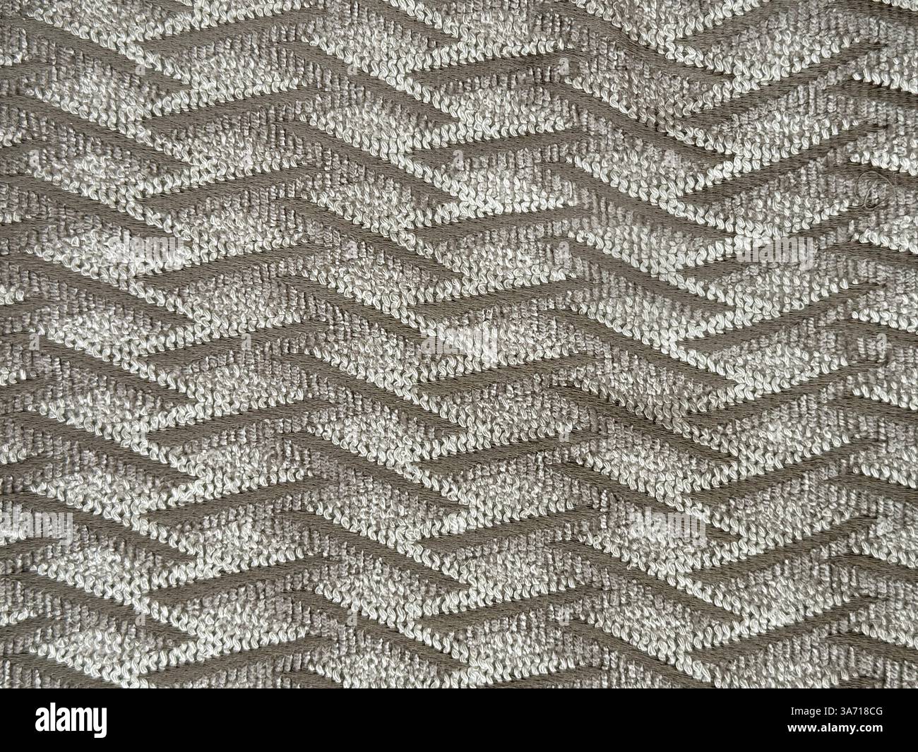 Primo piano di tessuto grigio marrone con motivo di filettatura ondulata. Tessuto marrone con tessitura a chevron, fondo senza cuciture. Foto Stock