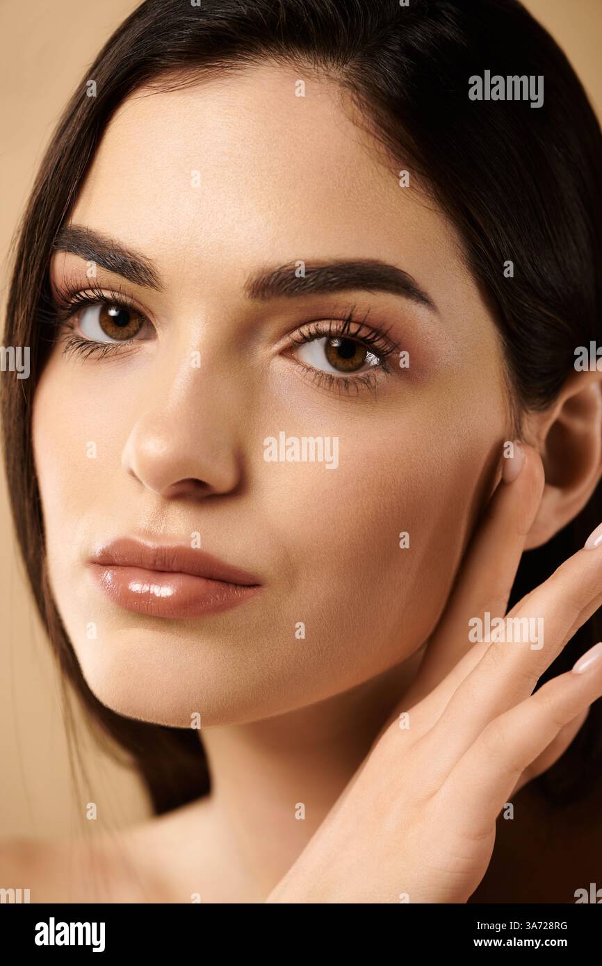 Una giovane donna mette in risalto la sua pelle luccicante e impeccabile in un ambiente di studio incentrato sulla bellezza. Foto Stock