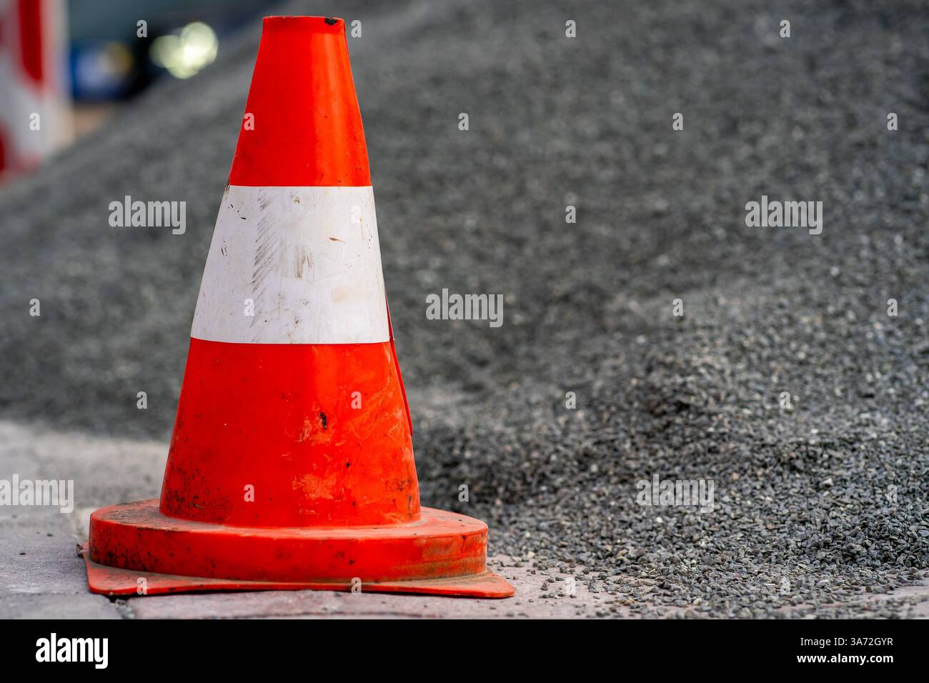 Vista di un cono stradale in piedi vicino a una montagna di ghiaia in un cantiere edile Foto Stock