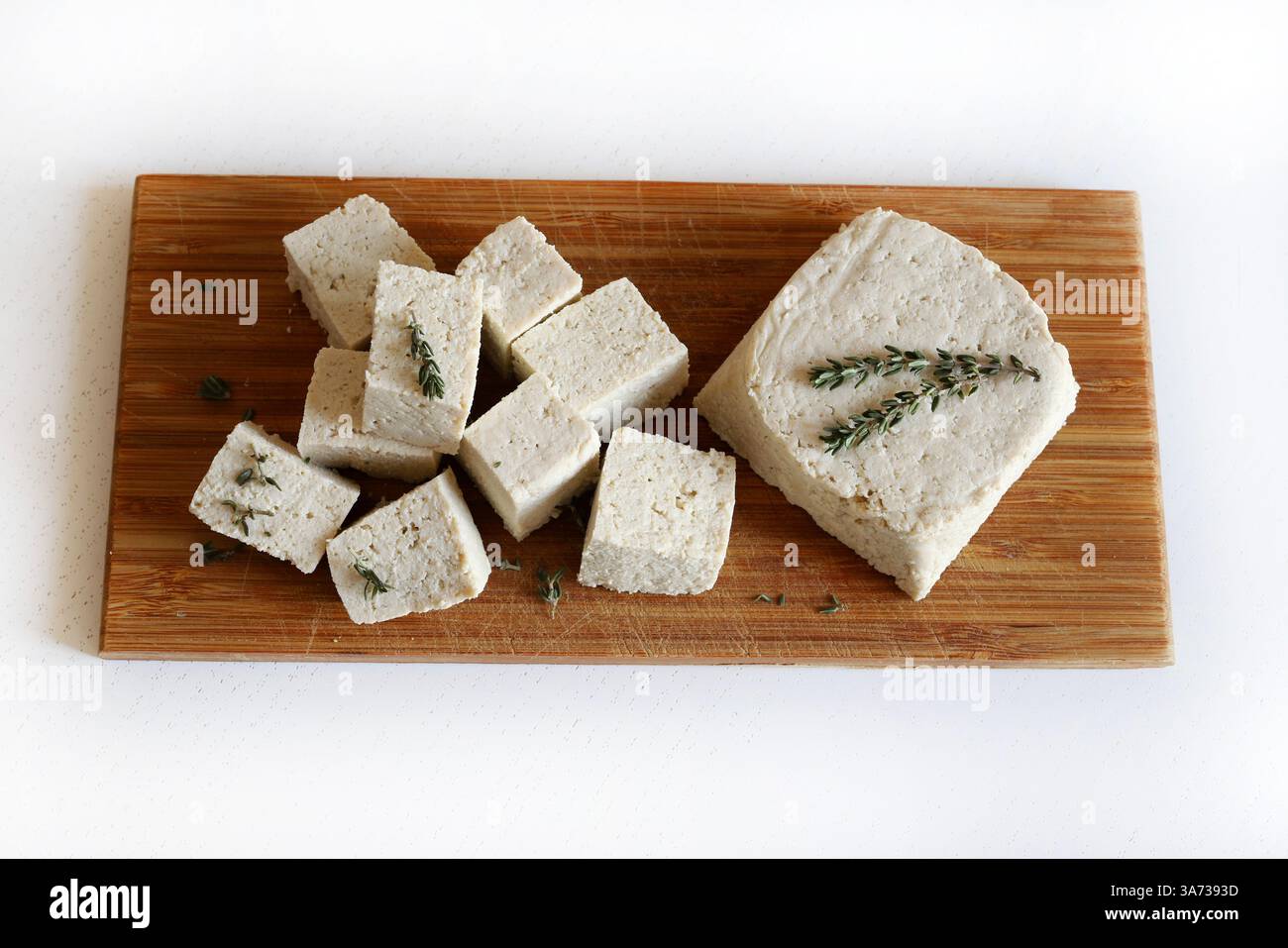 Cucina asiatica. Tofu o formaggio di soia. Tofu grezzo intero a fette ​​and, tofu bianco duro con cagliata di soia su un tagliere di legno. Formaggio vegetale. Cibo sano Foto Stock