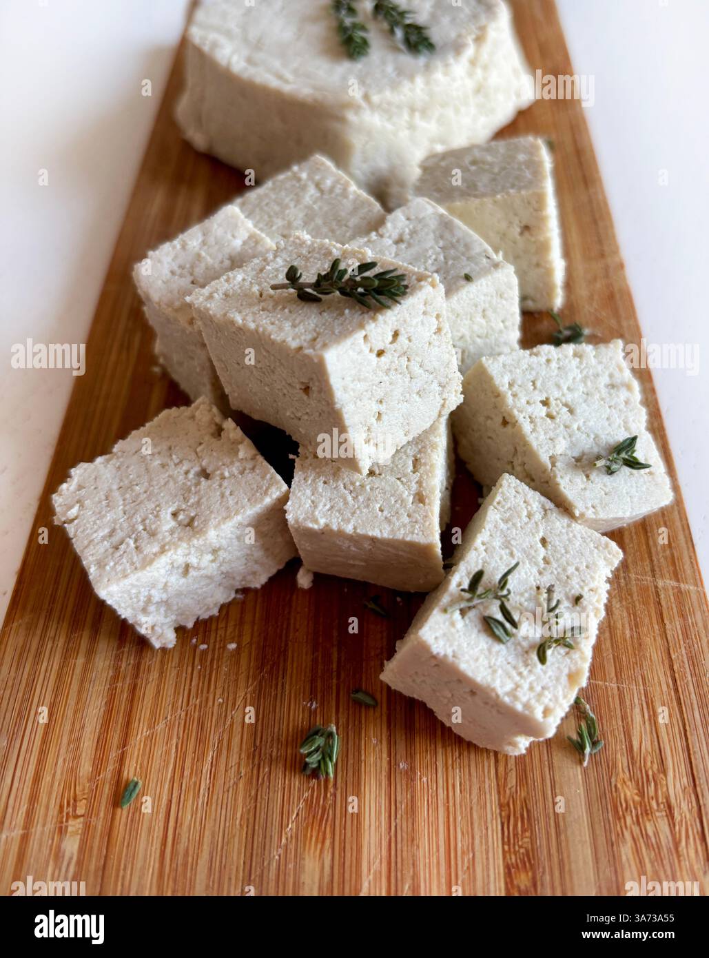 Cucina asiatica. Tofu o formaggio di soia. Tofu grezzo intero a fette ​​and, tofu bianco duro con cagliata di soia su un tagliere di legno. Formaggio vegetale. Cibo sano Foto Stock