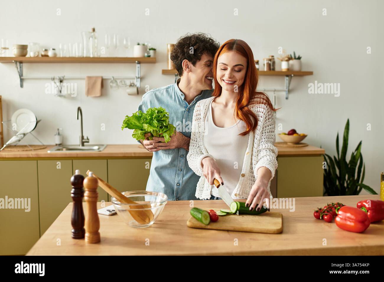 Una coppia condivide un momento tenero nella loro elegante cucina mentre preparano un pasto fresco insieme. Foto Stock