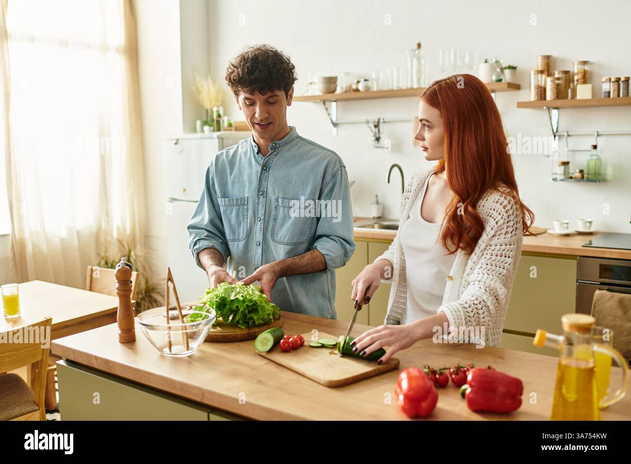 La giovane coppia condivide un momento delizioso mentre preparano un pasto fresco insieme a casa. Foto Stock