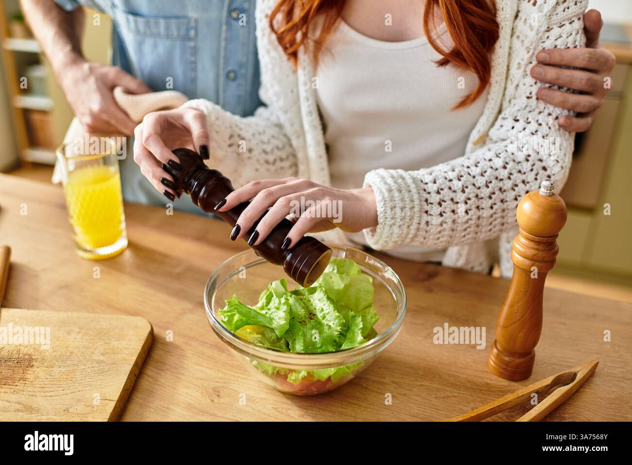 Una coppia amorevole condivide un momento di gioia in cucina mentre preparano un'insalata sana insieme. Foto Stock