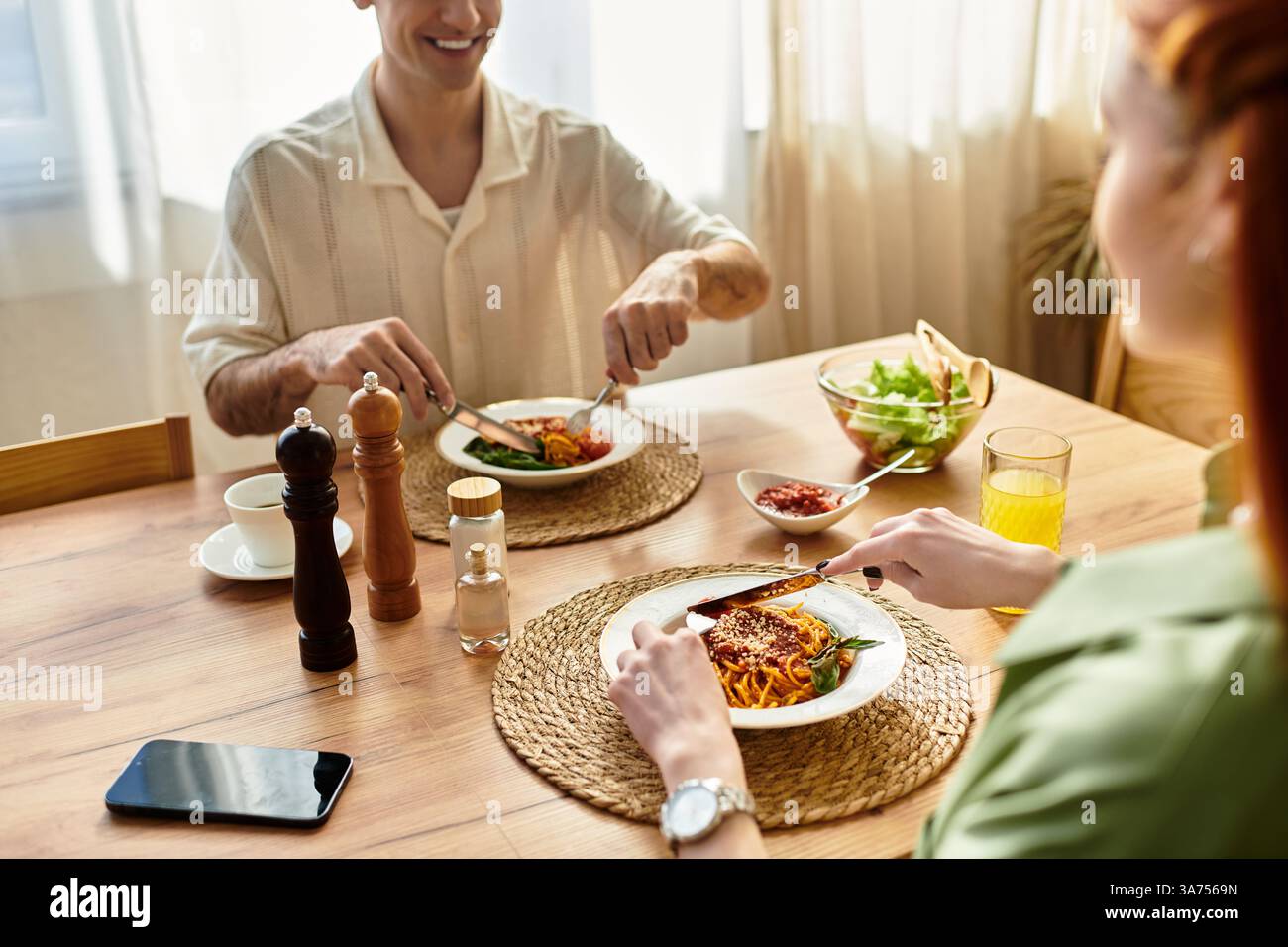Una coppia amorevole condivide una deliziosa cena a base di pasta a casa, assaporando ogni momento pieno di risate. Foto Stock