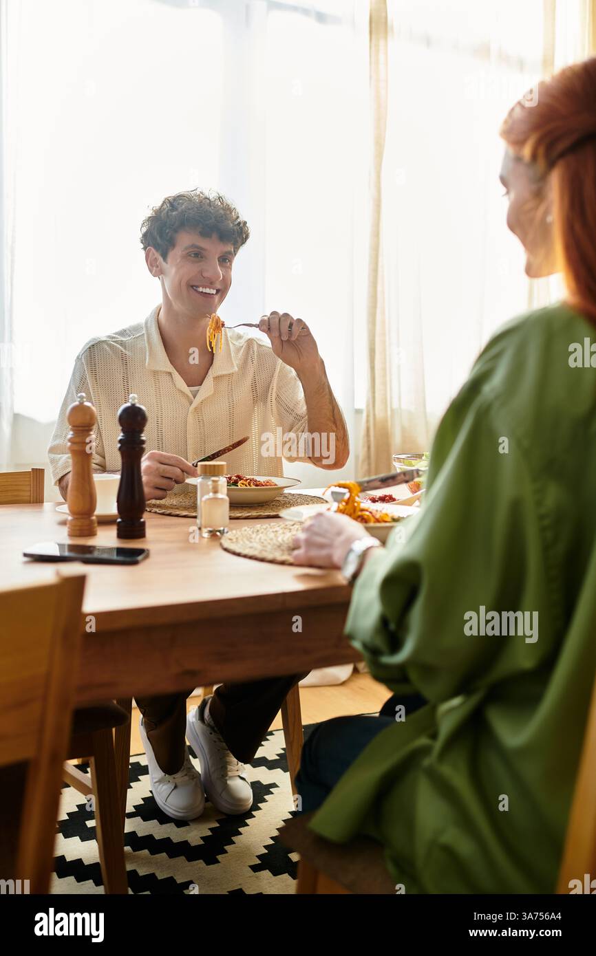 Una coppia amorevole condivide un momento caldo a casa, assaporando cibo delizioso e compagnia reciproca. Foto Stock