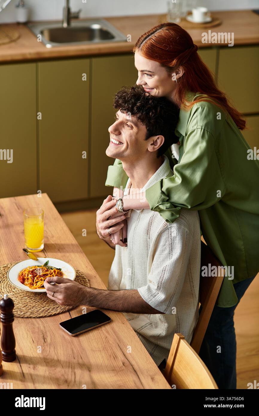 Una giovane coppia condivide un momento di gioia a casa mentre si gusta un pasto fatto in casa, irradiando amore. Foto Stock