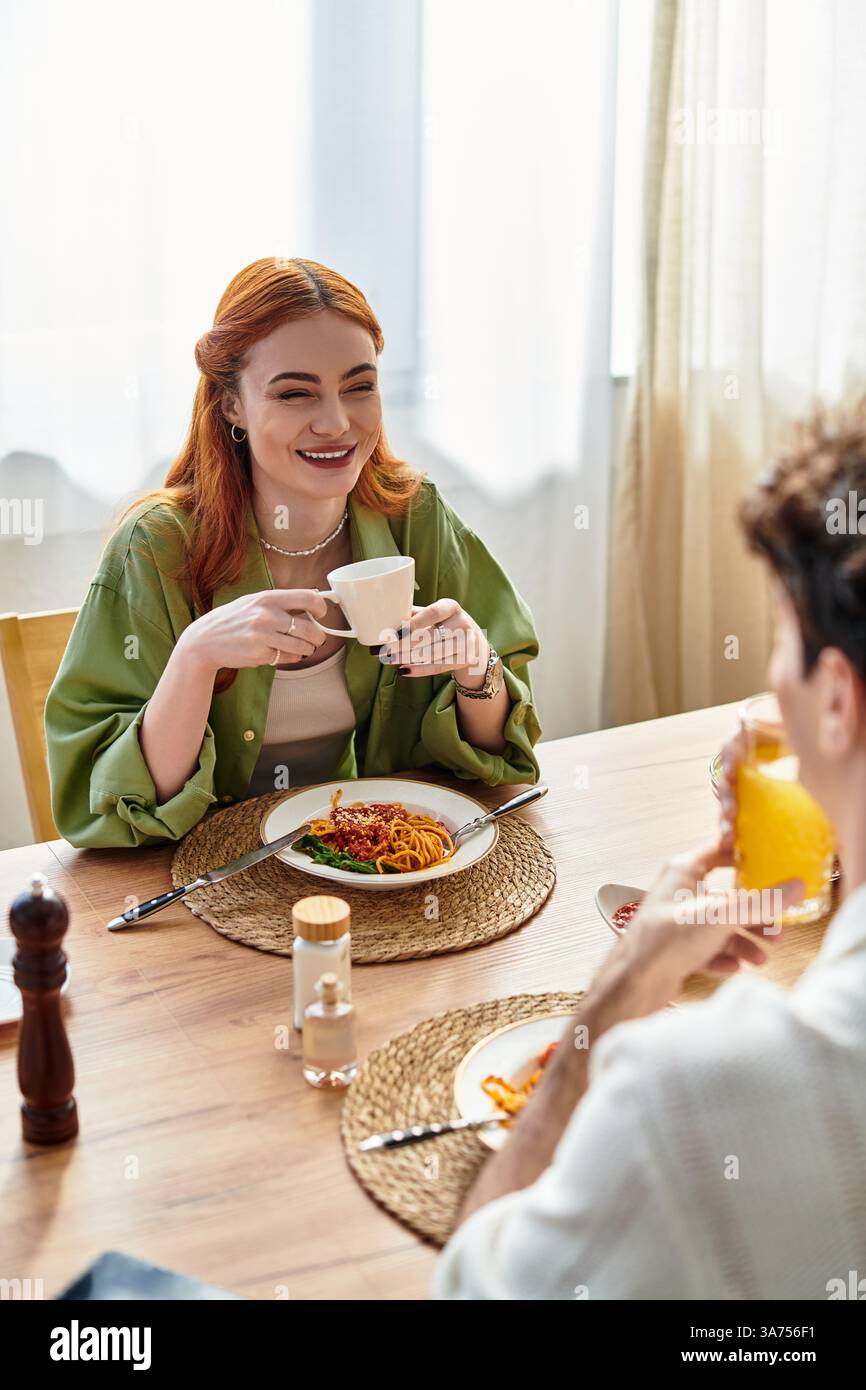 Due giovani amanti si godono un delizioso pasto insieme, sorridendo e assaporando il loro tempo a casa. Foto Stock