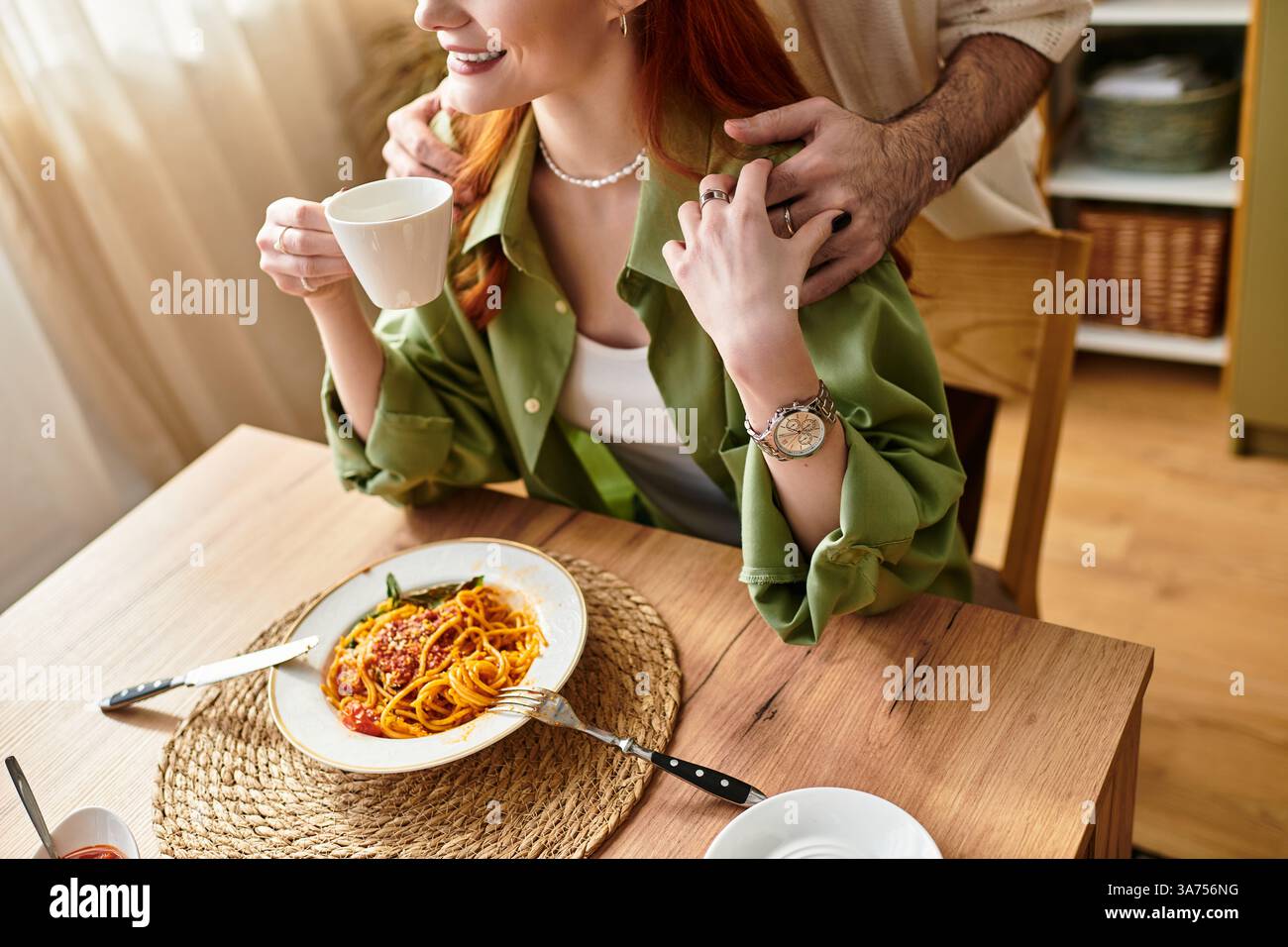 Una giovane coppia si diverte con un pasto delizioso a casa, regalando momenti di risate e calore insieme. Foto Stock