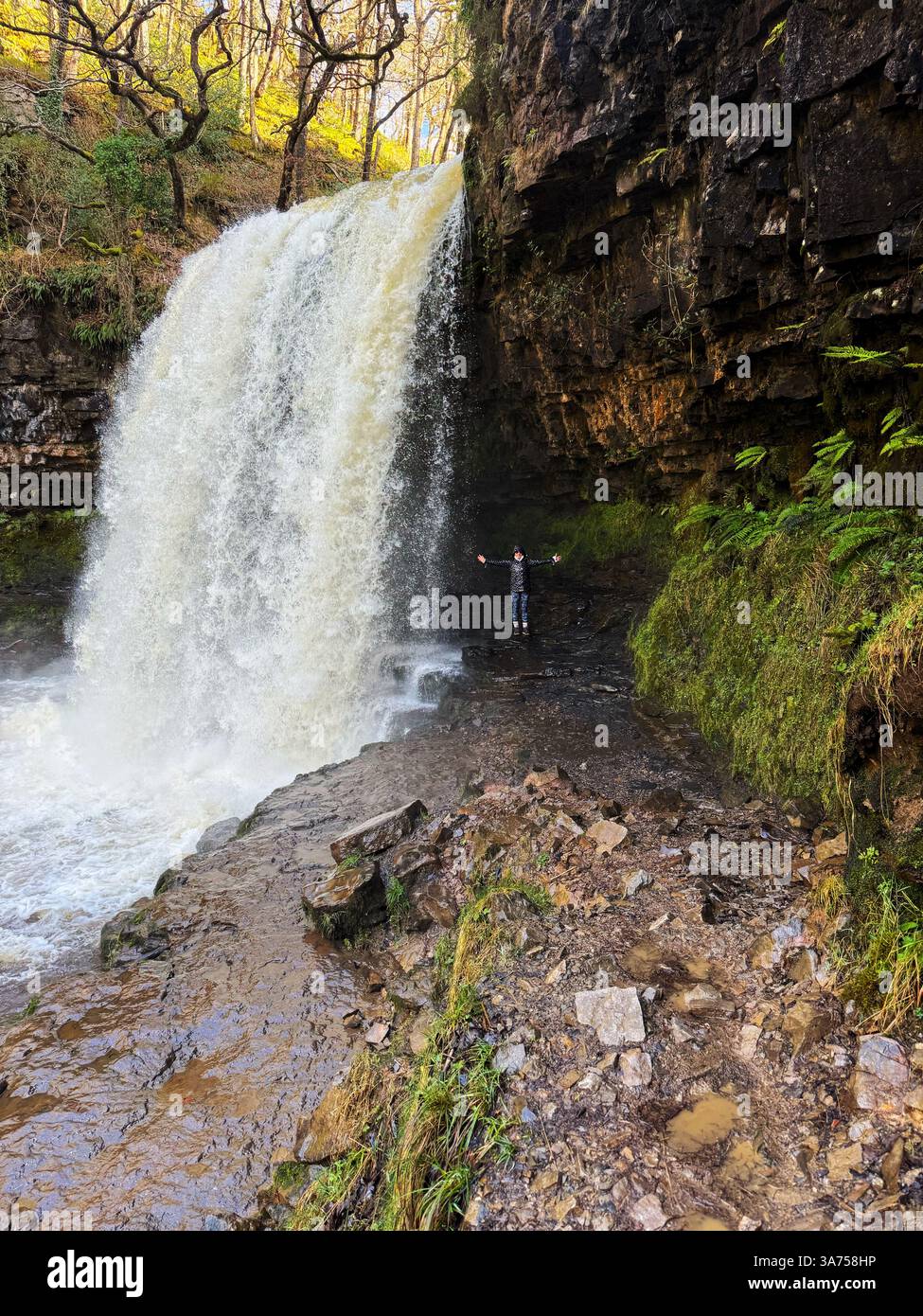 Donna sotto la cascata Sgwd Yr Eira, vale di Neath, Brecon Beacons (Bannau Brycheiniog). - Immagine stock catturata con smartphone