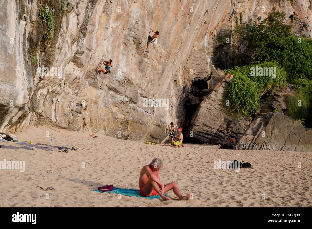 Gli scalatori scalano la ripida parete calcarea di Tonsai Beach, mentre nelle vicinanze si rilassa un po' di sole Foto Stock