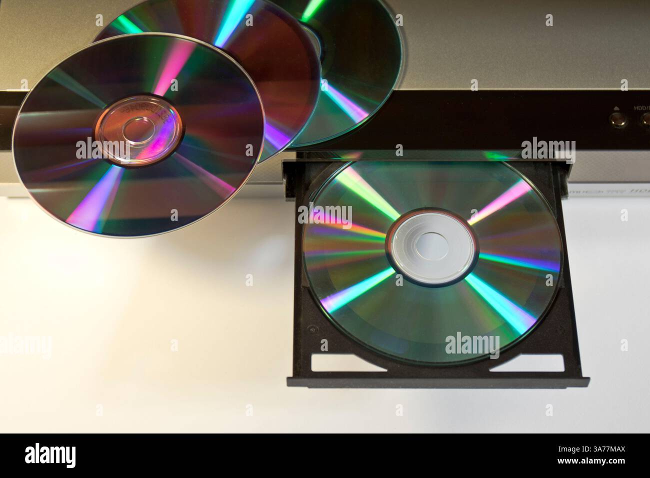 DVD e CD accanto a un lettore aperto con un disco inserito Foto Stock