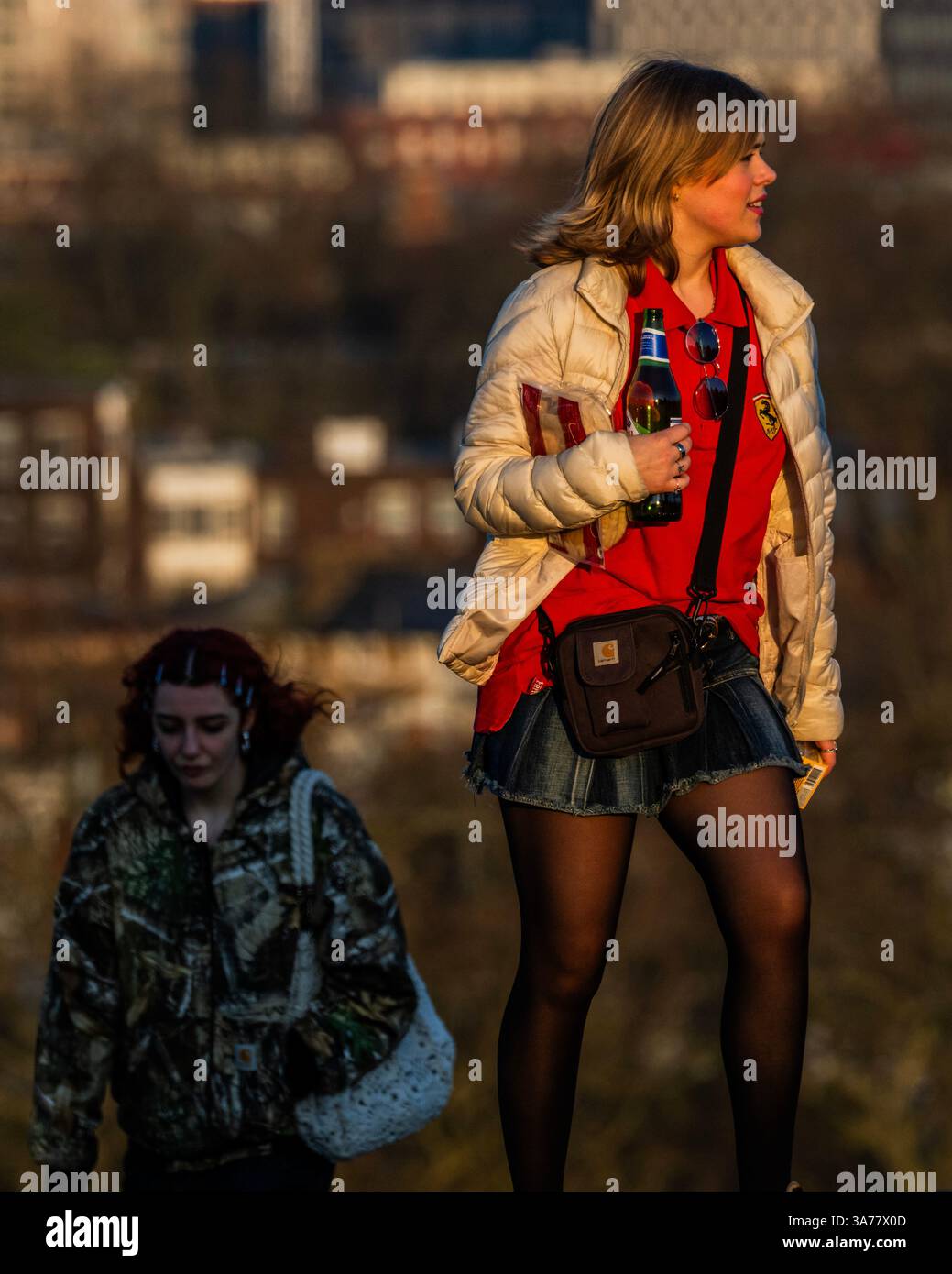 Londra, Regno Unito. 26 marzo 2025. Molti portano bevande e spuntini - i tramonti su Londra mentre i visitatori si avvicinano per godersi la vista dal clima caldo da Primrose Hill. Le vedute sono di Canary Wharf, della torre BT e della City di Londra. Crediti: Guy Bell/Alamy Live News Foto Stock