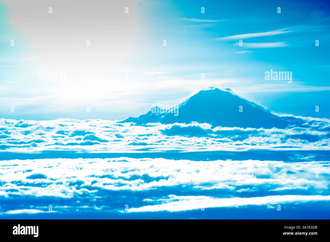 Cima del Monte Rainier che appare intorno alle nuvole, una vista dalla finestra di un jet liner. Foto Stock