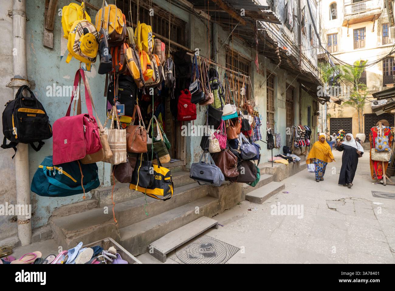 Un vicolo stretto fiancheggiato da negozi locali che vendono borse e accessori Zanzibar , Tanzania Foto Stock