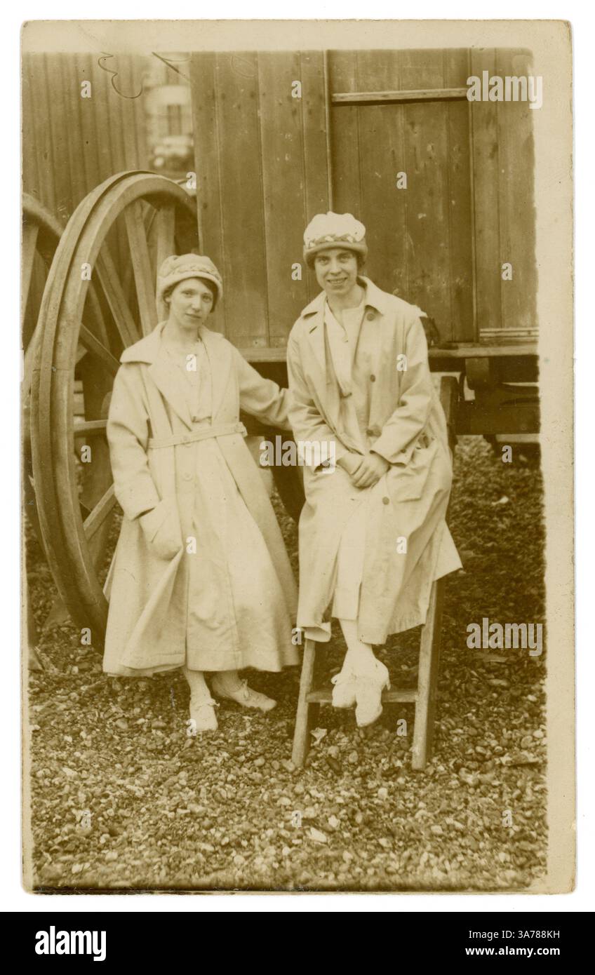 Cartolina originale dell'epoca della prima Guerra Mondiale di due donne che indossano costumi da bagno con soprabiti per il calore, berretti da bagno, sedute sui gradini di una capanna da bagno. Regno Unito circa 1917 Foto Stock