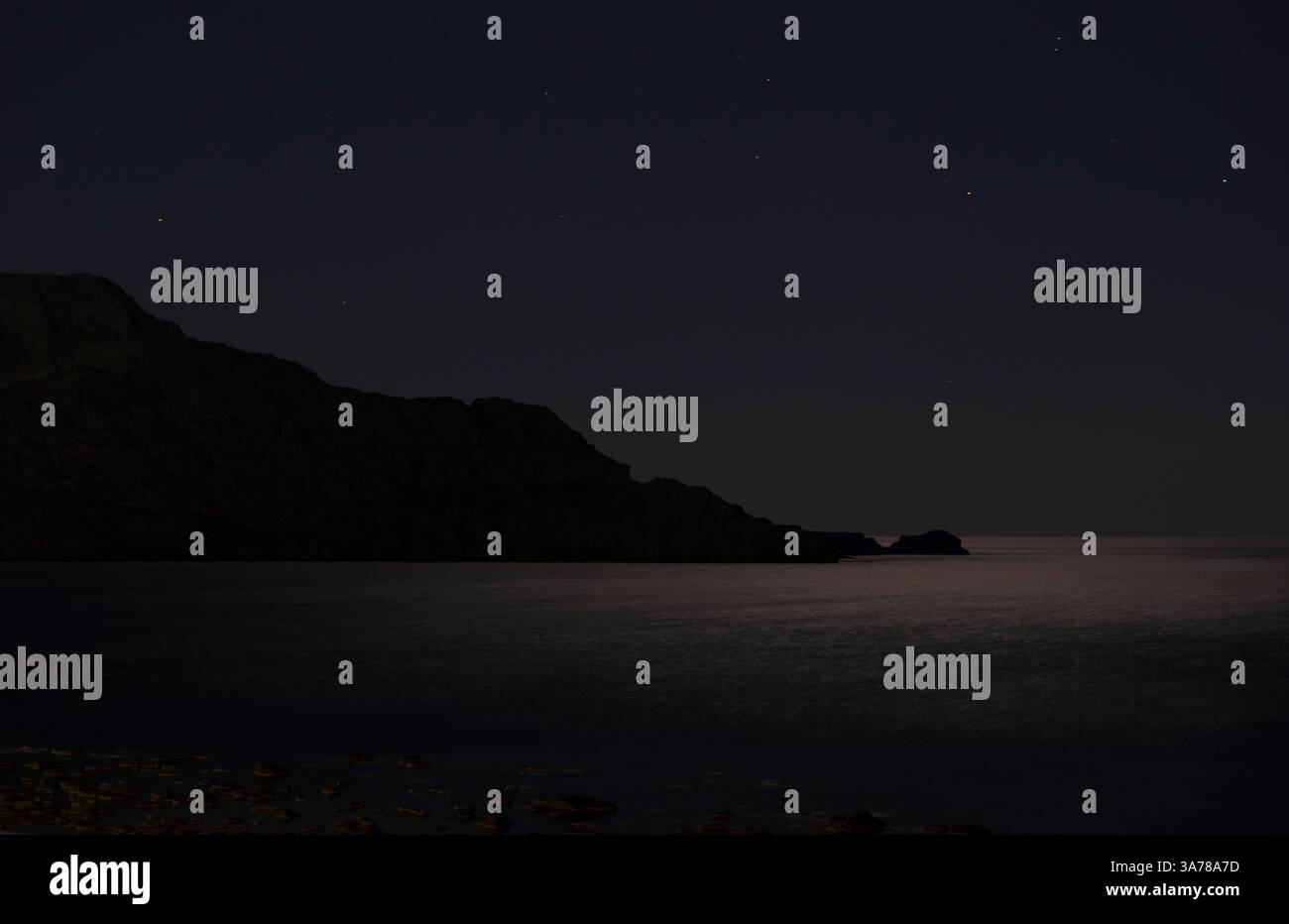 Oceano illuminato dalla luna con costa rocciosa scura, Mar libico, Creta Foto Stock