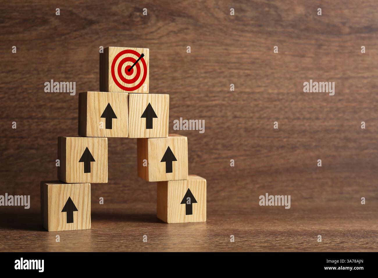 Targeting. Piramide di cubi con frecce che puntano ad uno con un mirino sulla parte superiore su sfondo di legno Foto Stock