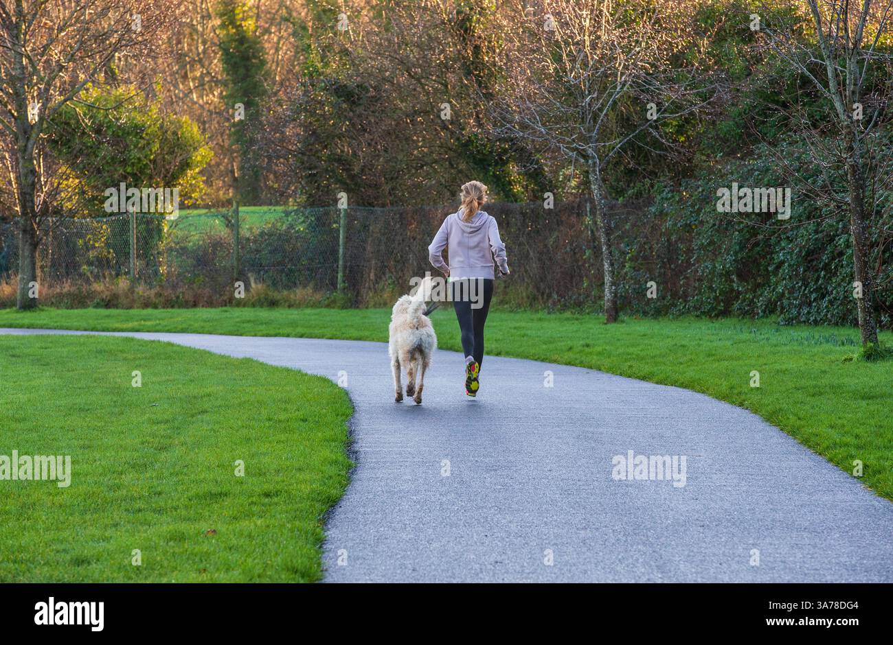 donna che corre con il cane Foto Stock