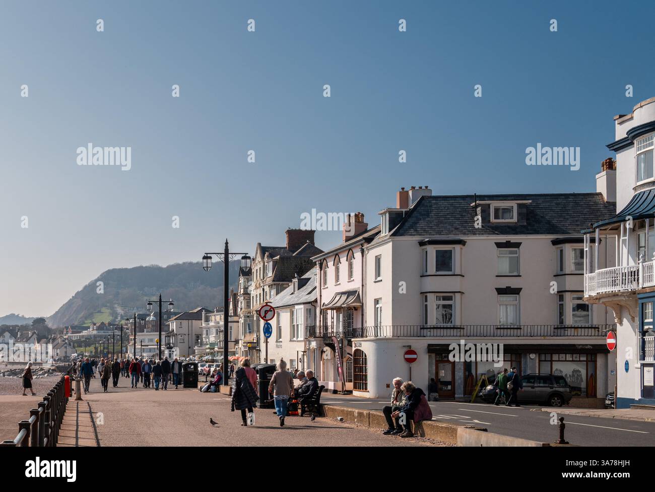 Passeggiata a Sidmouth all'inizio della primavera con folle di persone che camminano e si siedono con la città come sfondo. East Devon, Inghilterra Regno Unito. Foto Stock
