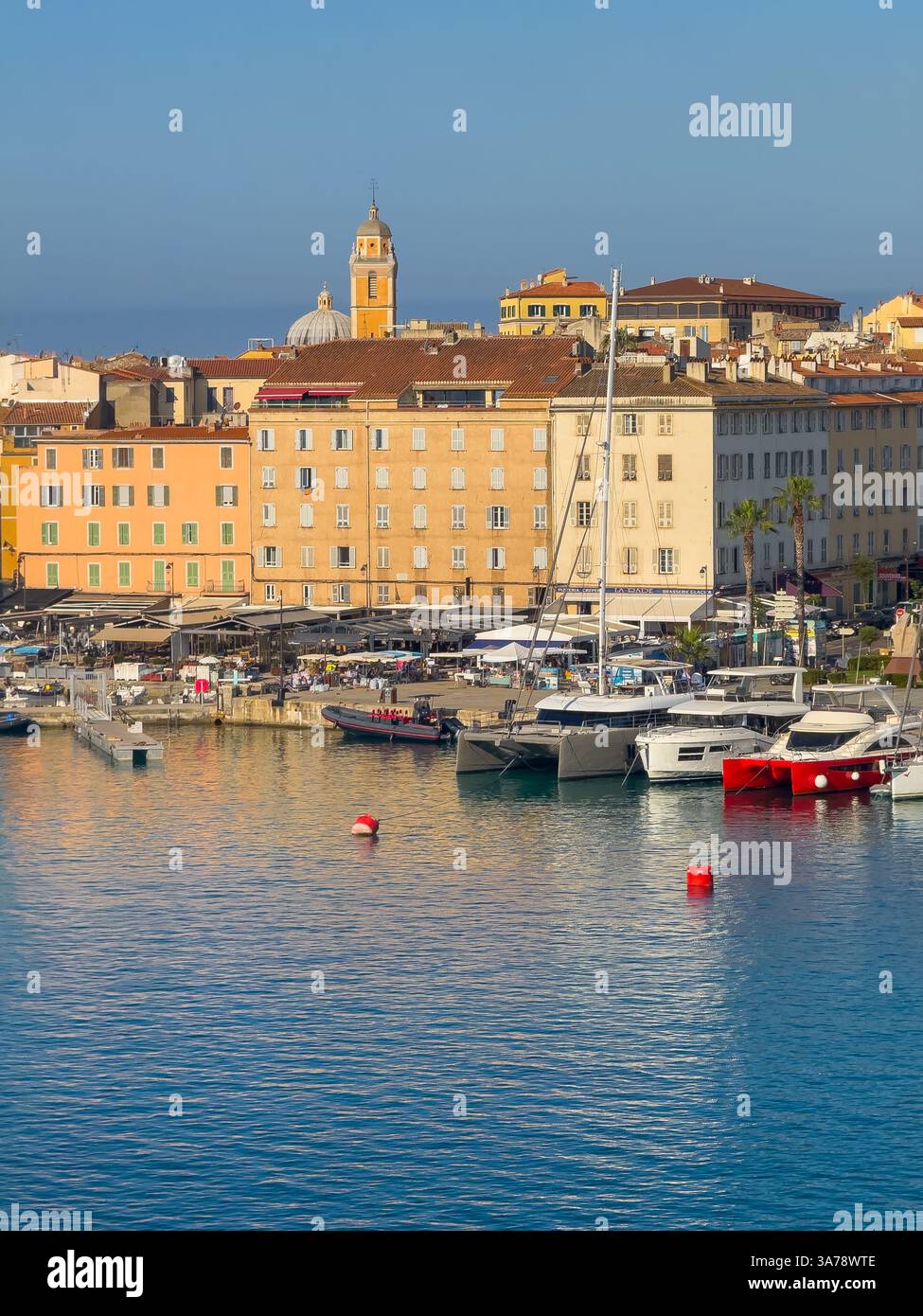 Ajaccio, Corsica, Francia 8 luglio 2024: Lungomare del porto con la cattedrale di Santa Maria Assunta che torreggia su un edificio a più piani. Barche attraccate Foto Stock