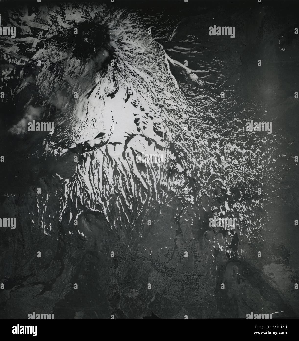 Una drammatica immagine topografica aerea dell'Etna, l'iconico stratovulcano siciliano, catturato da un aereo da ricognizione militare statunitense nell'Italia del dopoguerra. Scattata alla fine degli anni '1940, la fotografia rivela flussi lavici ricoperti di neve e fessure radiali che scendono dal cratere sommitale. Questa immagine è stata utilizzata in indagini geologiche per valutare l'attività vulcanica e il terreno sulla scia della seconda guerra mondiale Foto Stock