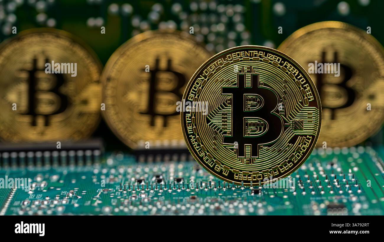 Moneda dorada Bitcoin en una placa de circuito electrónico de ordenador Foto Stock