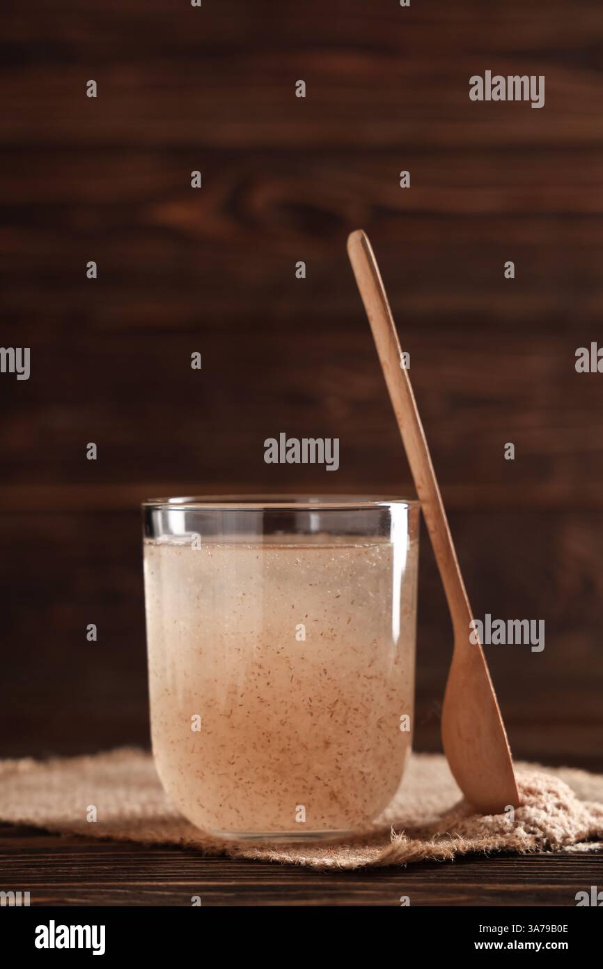Bicchiere d'acqua con buccia di psico su fondo di legno Foto Stock