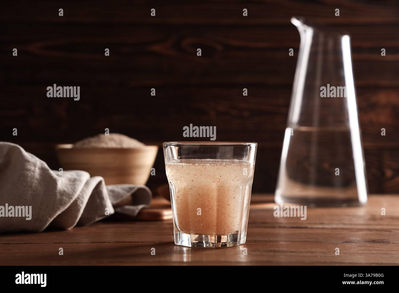 Bicchiere d'acqua con buccia di psico su fondo di legno Foto Stock