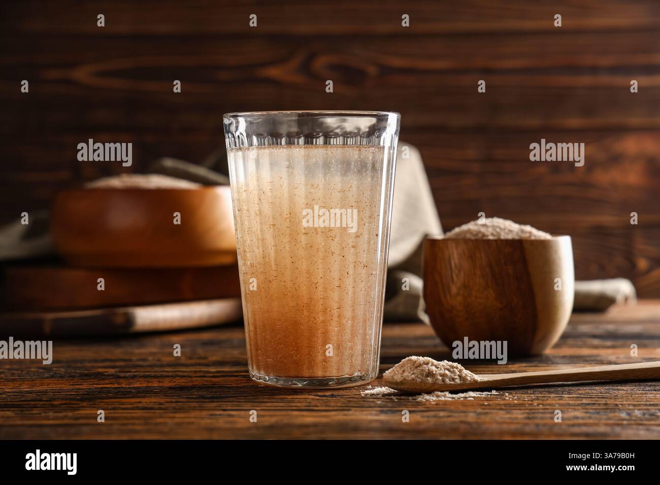 Bicchiere d'acqua con buccia di psico su fondo di legno Foto Stock