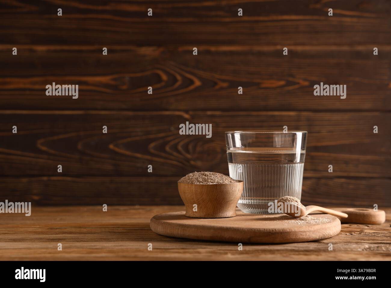 Bicchiere d'acqua con buccia di psico su fondo di legno Foto Stock