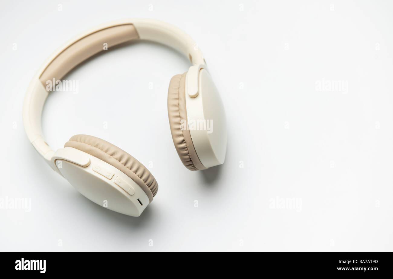 Cuffie wireless beige e bianche isolate su sfondo bianco, che rappresentano l'ascolto di musica, il piacere del podcast o la comunicazione audio Foto Stock