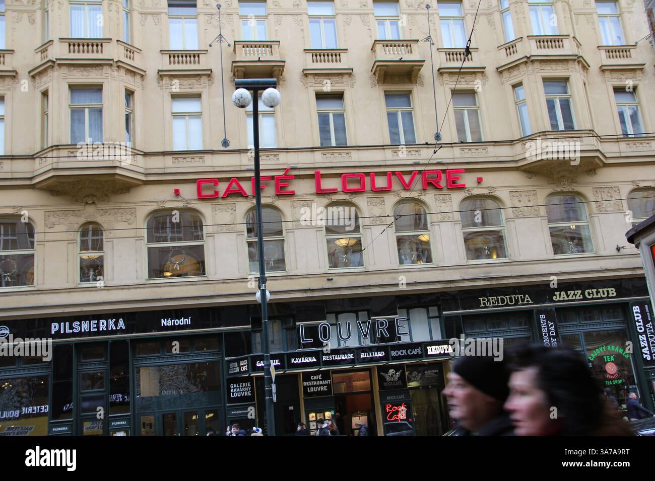 Vista esterna del storico Cafe Louvre e del Reduta Jazz Club su via NÃ¡rodnÃ a Praga, con architettura classica e segnaletica rossa. Foto Stock