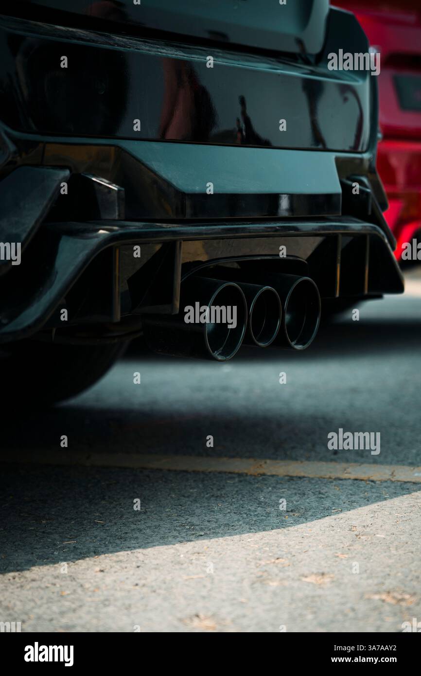 Doppio tubo di scarico lucido montato su un'auto sportiva nera, che ne mostra la perfetta integrazione e l'efficienza aerodinamica. Ideale per automobili di lusso Foto Stock