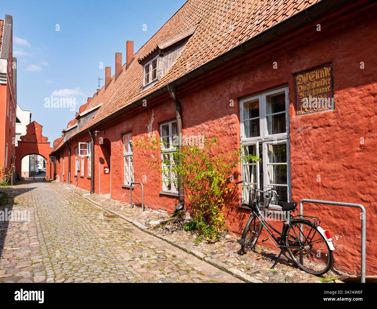 Strada stretta con storiche case in mattoni rossi e arco a Heilgeistkloster, monastero dello Spirito Santo, nella città vecchia di Stralsund, Meclemburgo-Vorpommern, Foto Stock