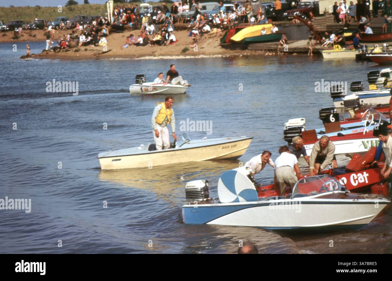 Una scena vivace degli anni '1960 che cattura un'emozionante giornata di corse su motoscafi su un fiume nel Regno Unito, girata su una pellicola slide da 35 mm. Le folle si radunano lungo la riva per allietare i concorrenti mentre le barche dai colori vivaci si allineano e corrono sull'acqua. Foto Stock