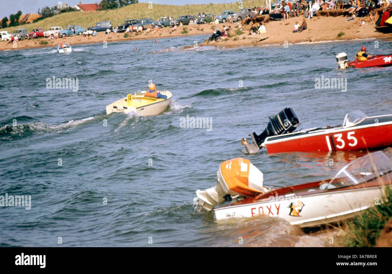 Una scena vivace degli anni '1960 che cattura un'emozionante giornata di corse su motoscafi su un fiume nel Regno Unito, girata su una pellicola slide da 35 mm. Le folle si radunano lungo la riva per allietare i concorrenti mentre le barche dai colori vivaci si allineano e corrono sull'acqua. Foto Stock