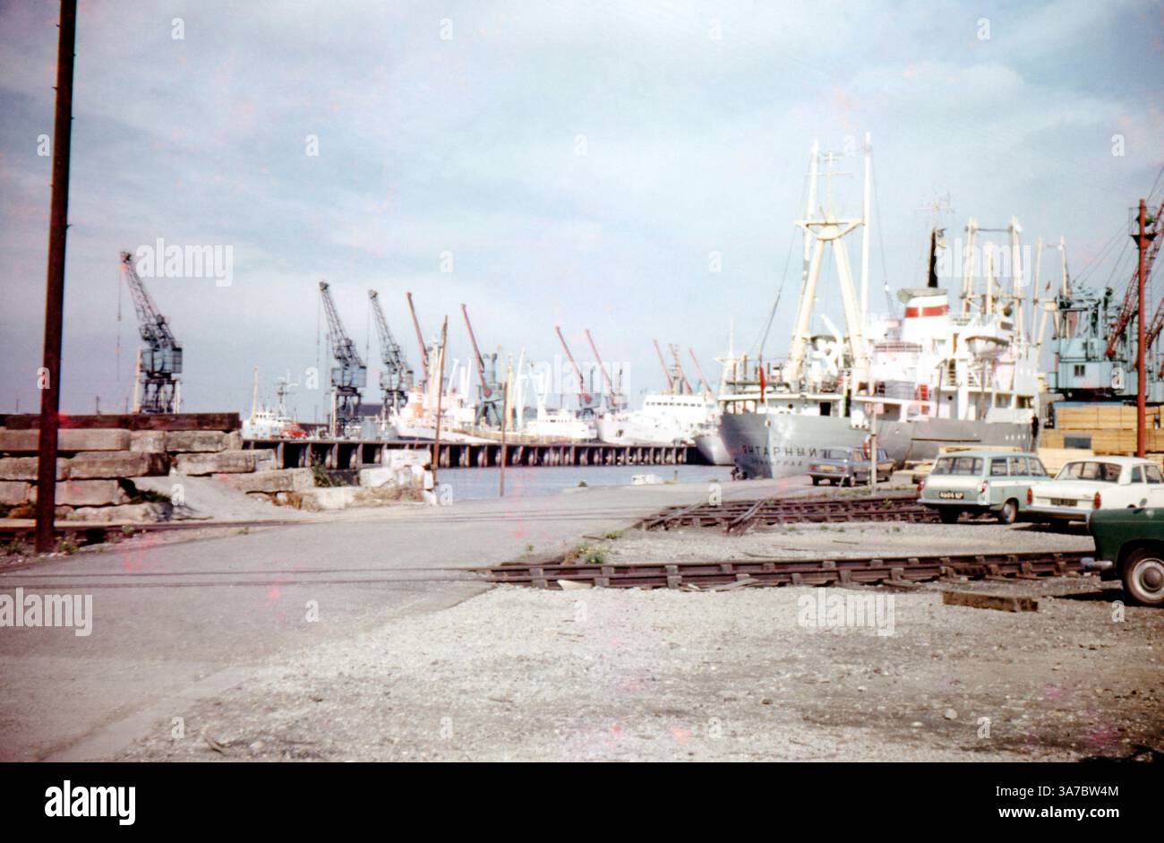 Una scena movimentata a Falmouth Docks, Cornovaglia, Inghilterra, negli anni '1960 L'immagine mostra file di gru che fiancheggiano la banchina, con navi da carico attraccate, una con caratteri cirillici, evidenziando i collegamenti commerciali internazionali del porto. Foto Stock