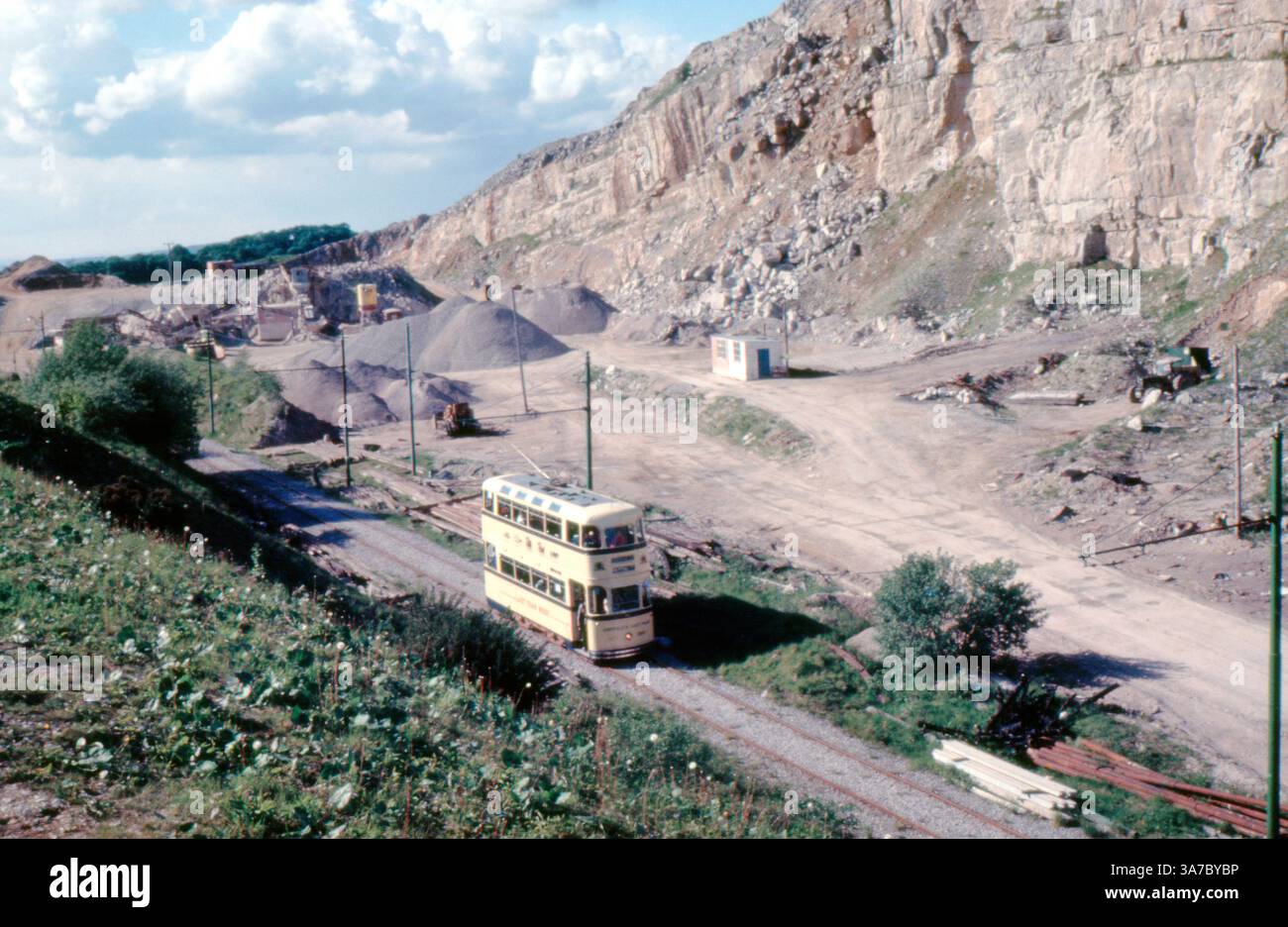 Una vista del 1960 del Crich Tramway Museum nel Derbyshire, ripresa su pellicola da 35 mm. Un classico tram a due piani viaggia lungo un percorso attraverso un paesaggio di cava funzionante, mostrando una miscela unica di patrimonio industriale e conservazione del trasporto vintage in un paesaggio rurale panoramico. Foto Stock