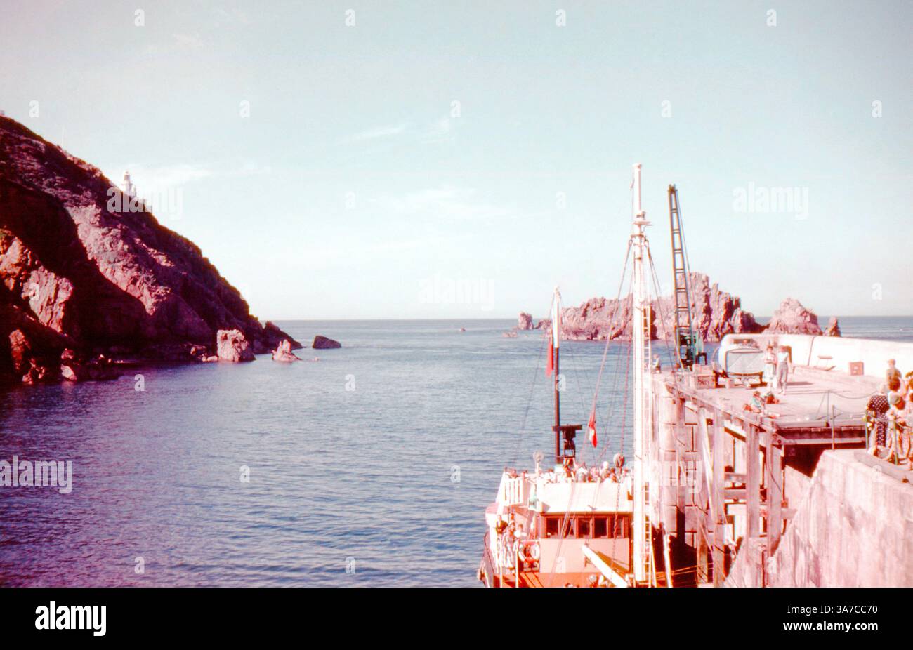 Una vista del 1960 del porto sull'isola di Sark, con una nave passeggeri attraccata e visitatori che sbarcano. Foto Stock