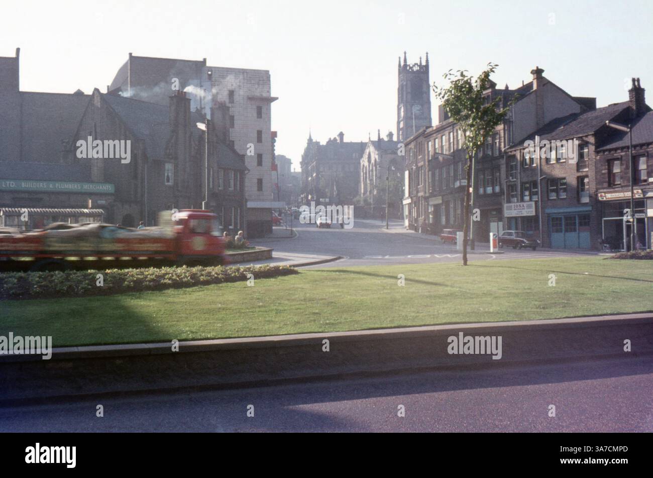 Una vista del centro di Huddersfield nei primi anni '1970, che mostra una tranquilla scena di strada con negozi d'epoca, veicoli e la torre prominente della chiesa di San Pietro in lontananza. Fotografato all'incrocio tra Kirkgate e Southgate. Foto Stock