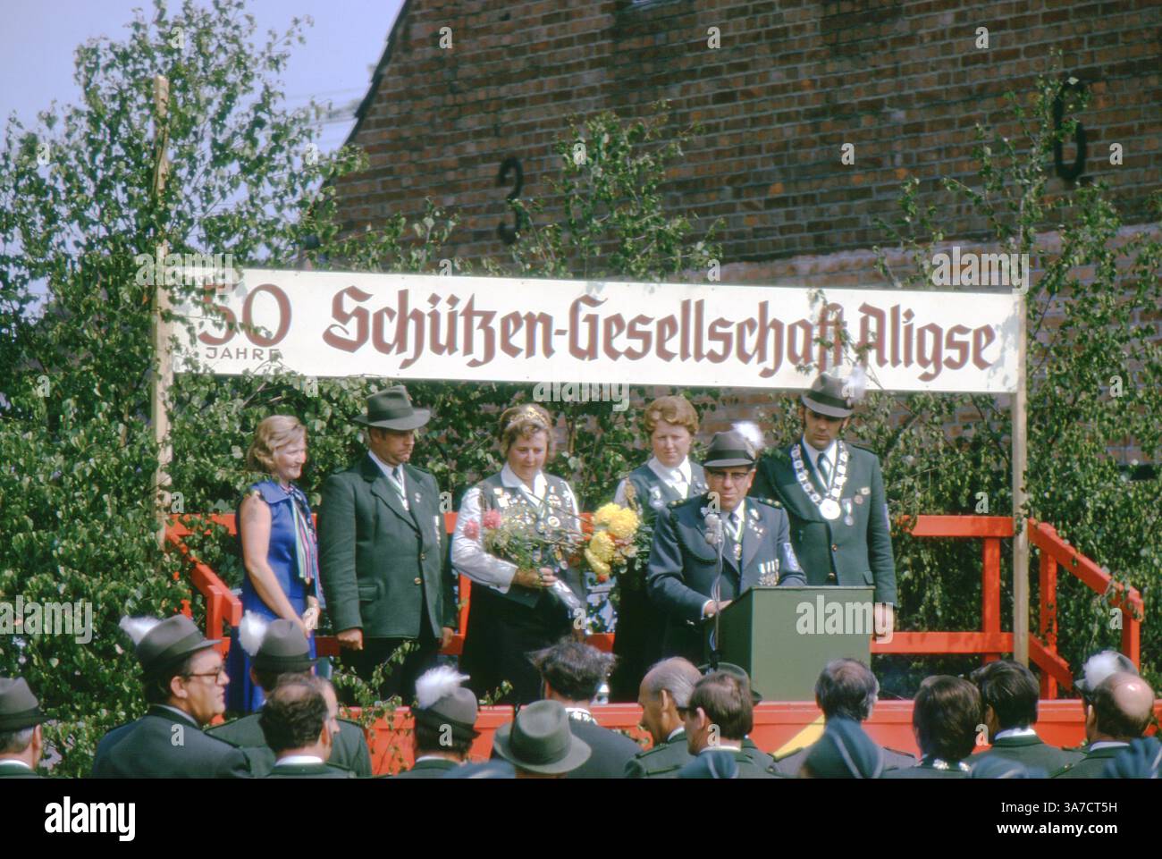 Una cerimonia formale durante il 50 Schützen anniversario della Schützenfest-Gesellschaft Aligse nel 1974, parte delle tradizionali celebrazioni. I membri della società, tra cui il Schützenkönigin regnante, si alzano su un palcoscenico decorato mentre un discorso viene tenuto a una folla riunita. Foto Stock