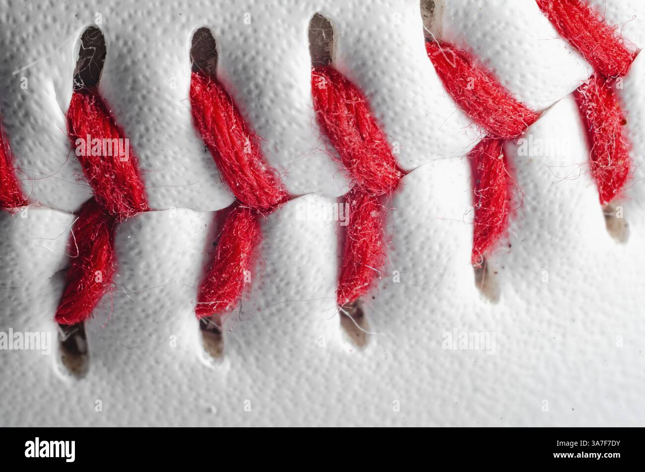 Vista macro delle cuciture rosse da baseball su pelle bianca per attrezzature sportive Foto Stock