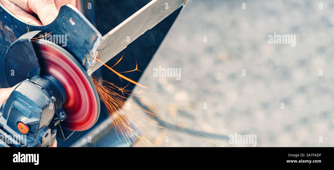 Utilizzare a mano una smerigliatrice angolare per tagliare il metallo con scintille in cantieri edili all'aperto Foto Stock