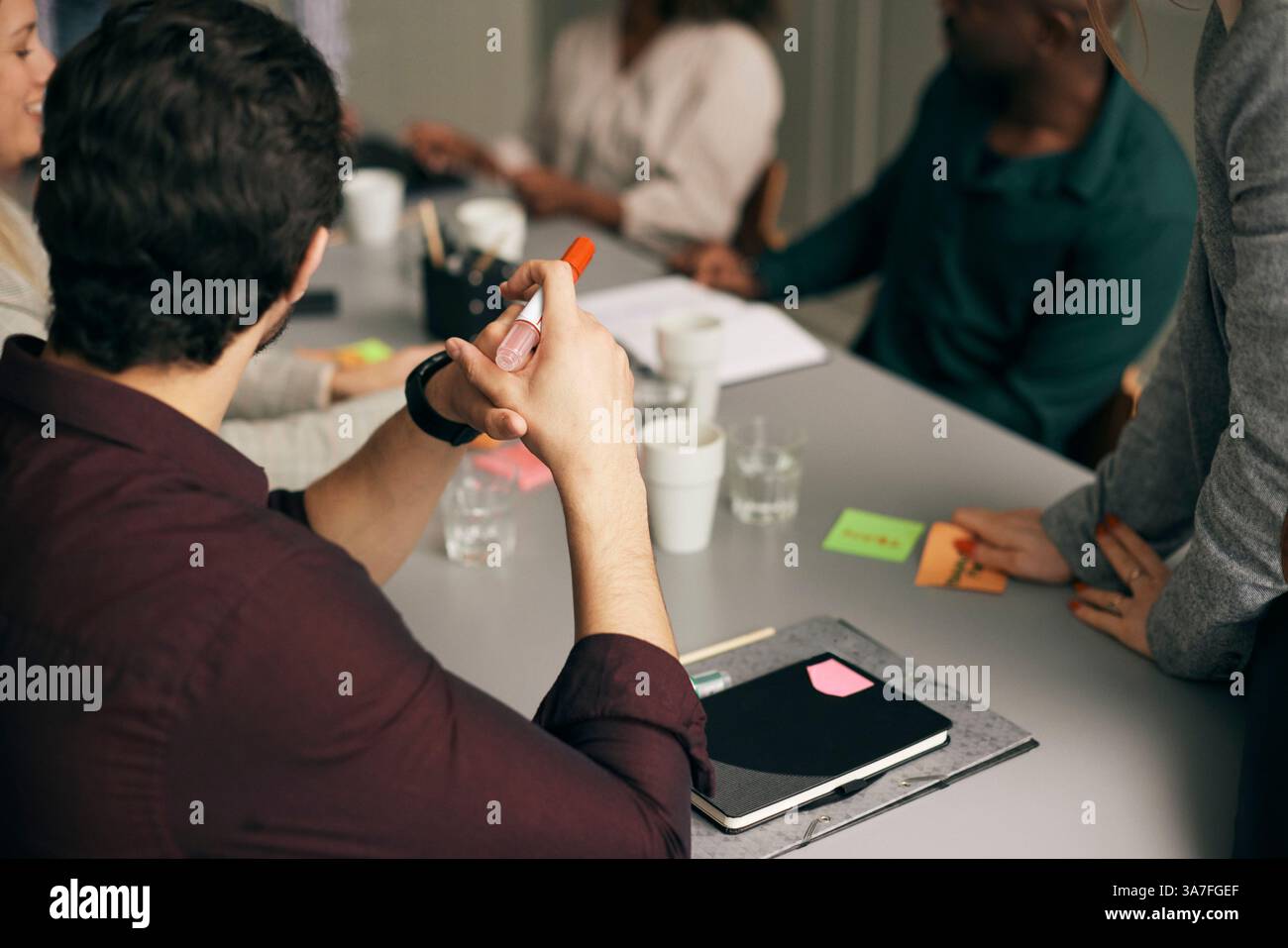 Vista ad angolo alto di un professionista che tiene la punta di feltro al tavolo nella sala riunioni dell'ufficio Foto Stock