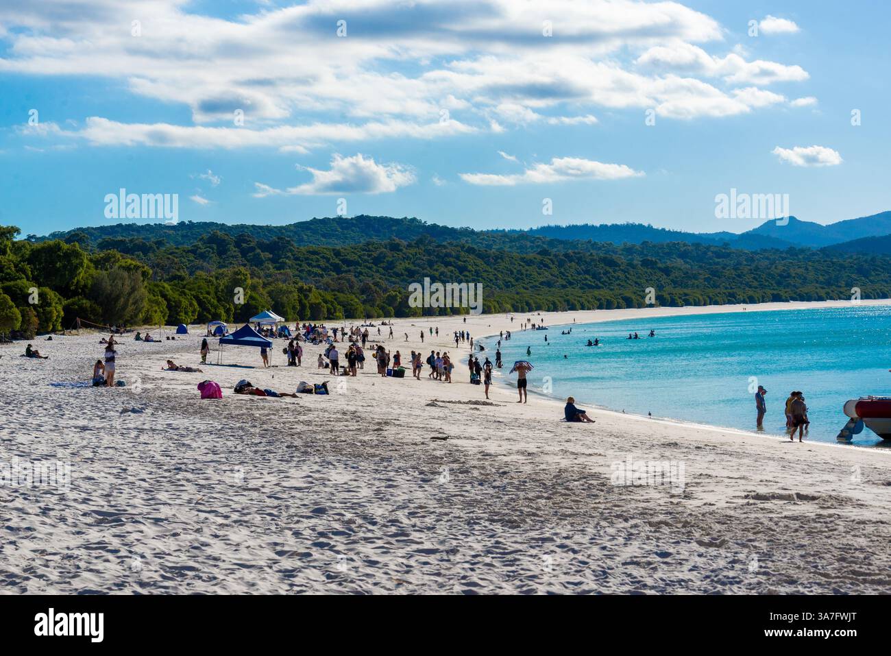 Giornata di sole a Whitehaven Beach con gente che si gode la splendida costa Foto Stock
