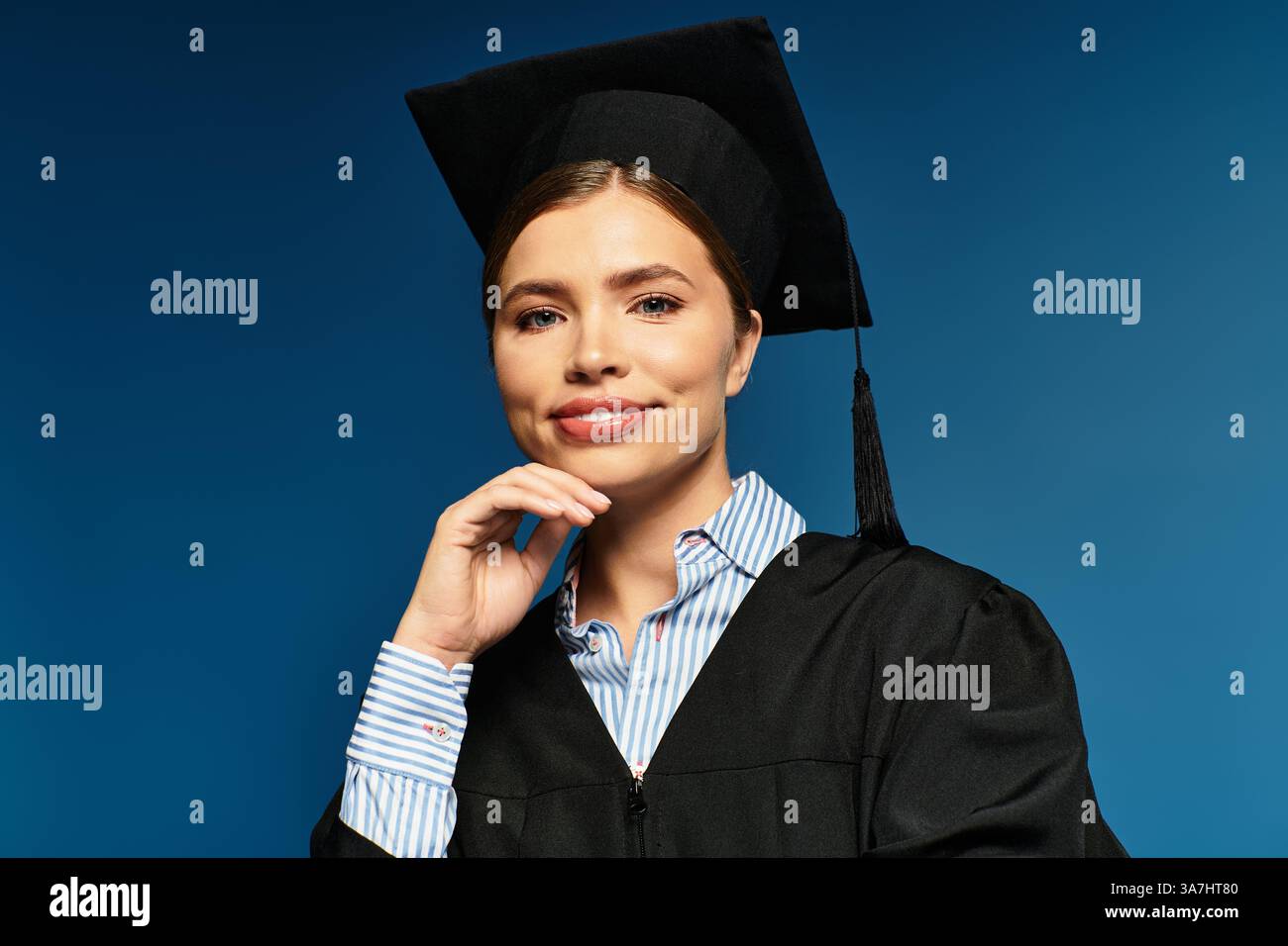 Una giovane donna con cappello e abito si posa con fiducia su uno sfondo blu, irradiando gioia. Foto Stock