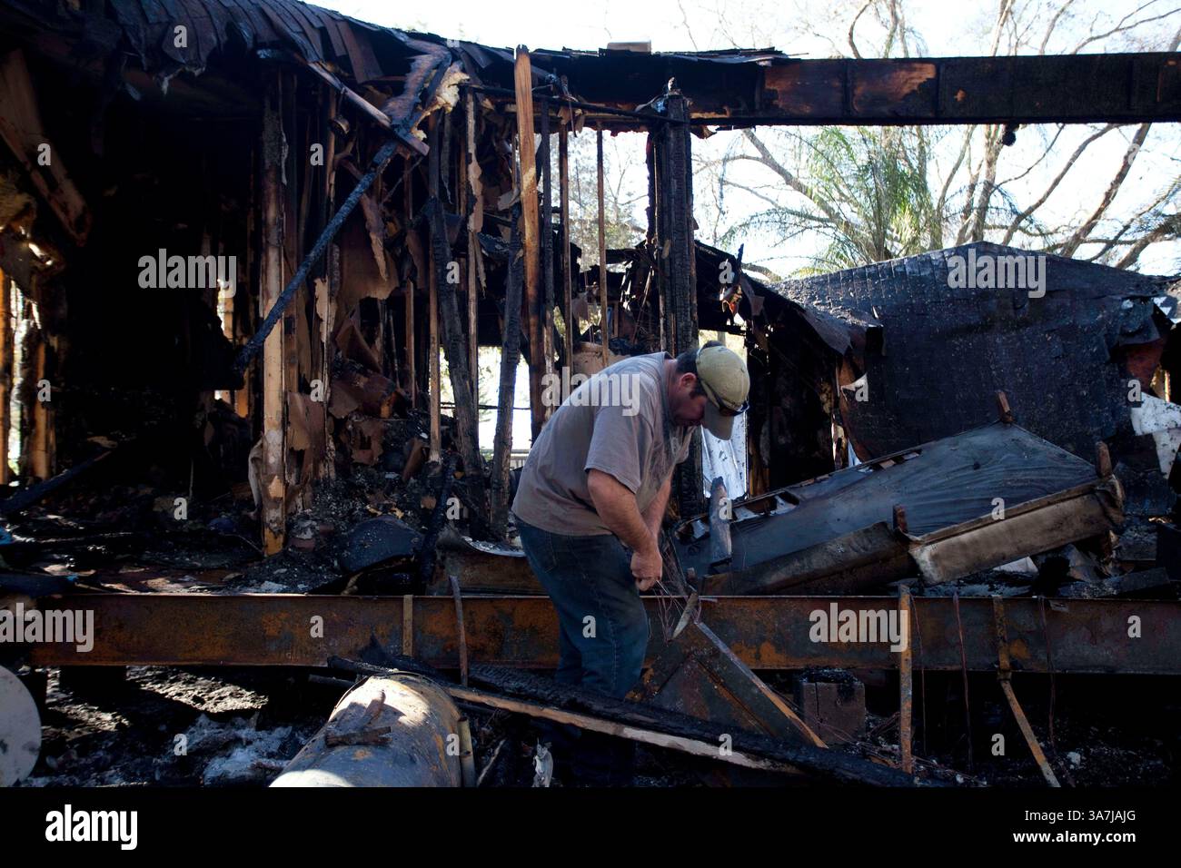 23 gennaio 2013 - Tampa, Florida, Stati Uniti - ALAN REGISTER aiuta il vicino Anahin Arellano, non nella foto, a rimuovere il trailer del cablaggio dopo che un incendio di mezzanotte ha distrutto il trailer a doppia larghezza. L'incendio è stato causato da un coinquilino che ha installato un generatore per alimentare il rimorchio, ha detto Arellano, che si è svegliato per fumare prima di saltare fuori dalla finestra con la sua bicicletta. (Immagine di credito: © Carolina Hidalgo/Tampa Bay Times/ZUMAPRESS.com) Foto Stock