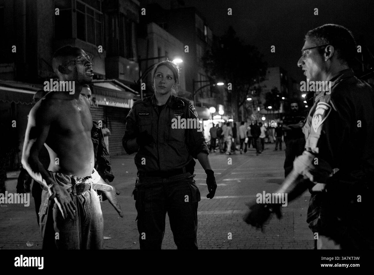 9 maggio 2012 - Tel Aviv, Israele - Tel Aviv la polizia interroga un migrante africano a Shapira dopo una sanguinosa lite tra due uomini. Shapira è stata la patria di un numero crescente di rifugiati africani e migranti economici, mentre la destra israeliana diventa sempre più intollerante della loro presenza. Ogni anno migliaia di uomini e donne rischiano la vita tentando di entrare illegalmente nella "Fortezza Europa”, dove le politiche di frontiera sempre più rigorose tengono il passo con le circoscrizioni elettorali sempre più orientate alla lotta contro l'immigrazione. Dal 1993, oltre 16.000 persone sono morte cercando di emigrare. Vengono dal Sudan, dalla Tunisia, dalla Sierra Leone, da me Foto Stock