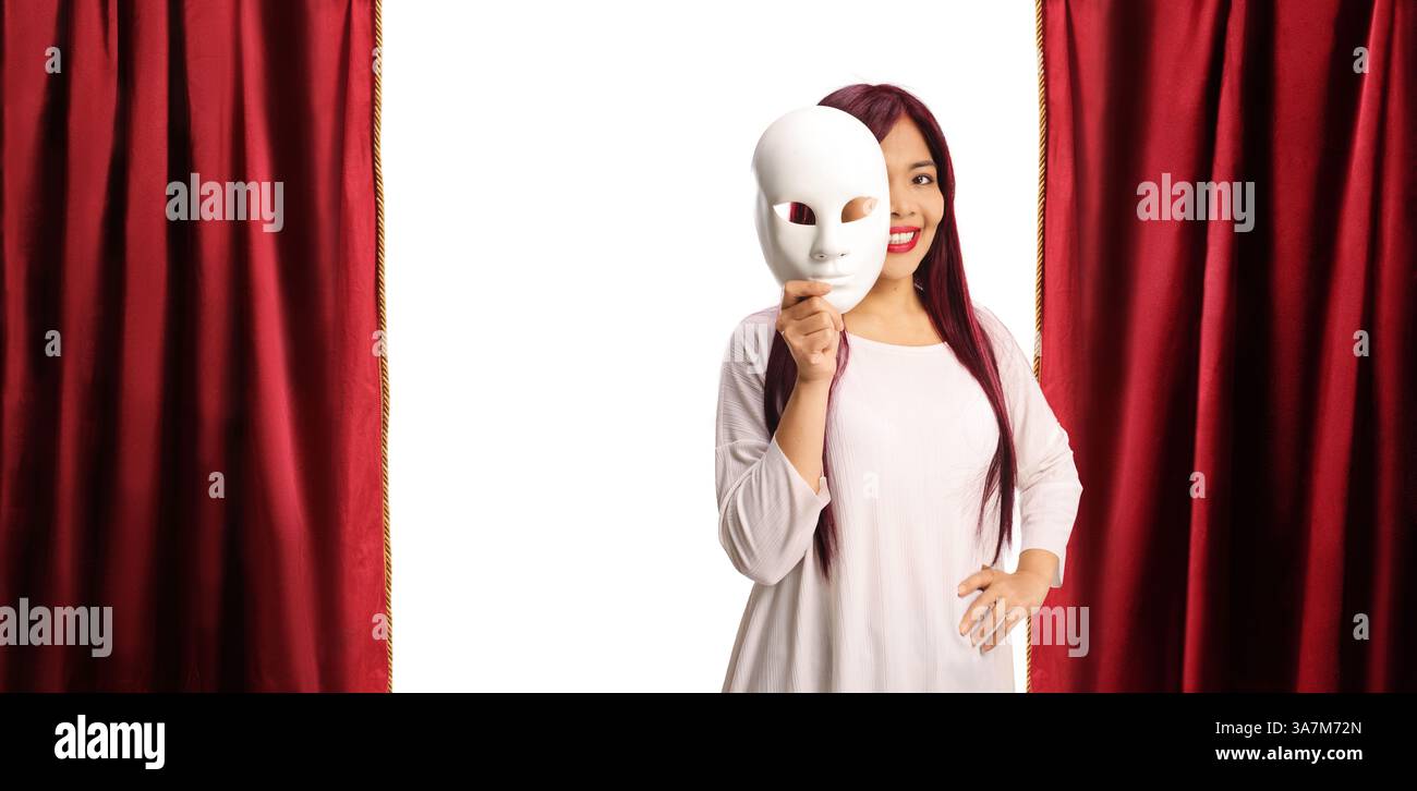 Donna asiatica che copre il viso con una maschera di teatro bianco sul palco con tenda rossa Foto Stock